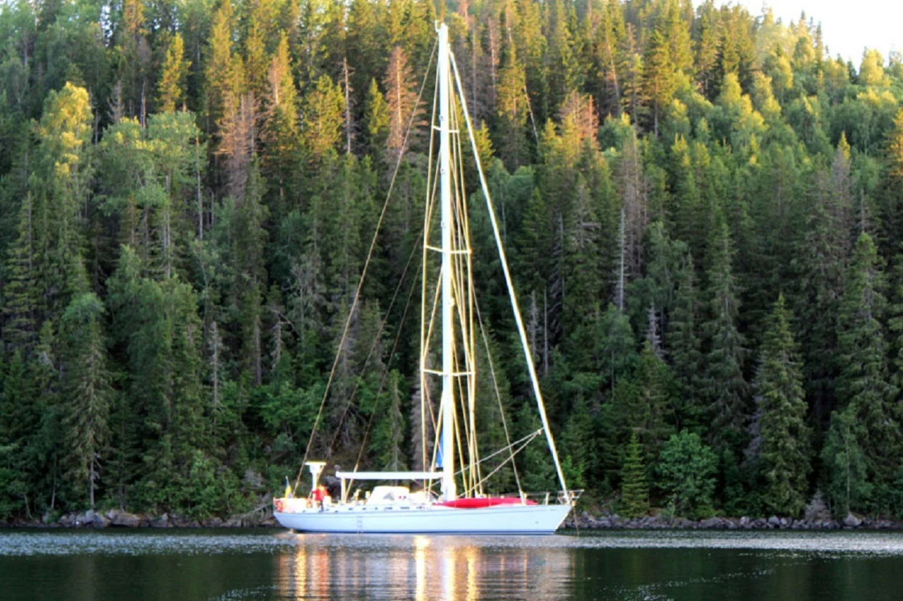Classic sailing yacht beside a wooded shore